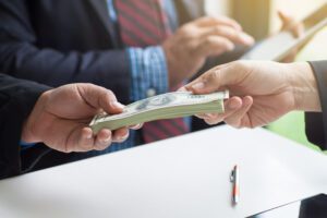 Money is exchanged between hands while someone does calculations in the background.