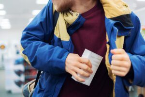 a thief slipping an item in coat