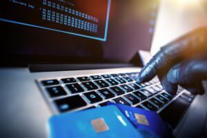A person in black gloves types a credit card number on a computer