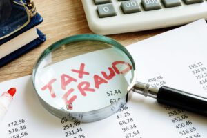 a document that says tax fraud in red letters under a magnifying glass