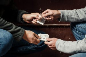 an image of hands trading pills or illegal drugs for cash