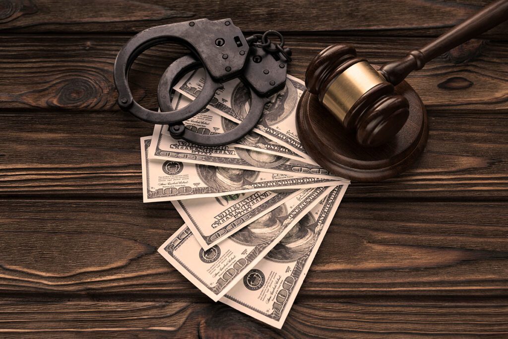 Handcuffs, gavel, and three 100 dollar bills on the background of a wooden table
