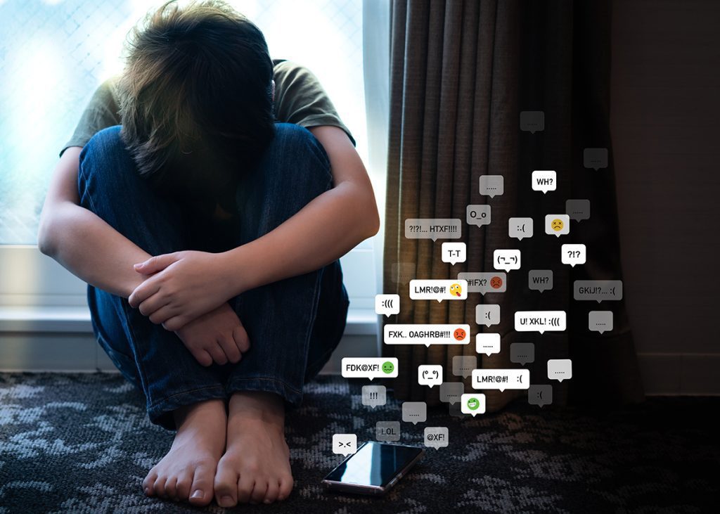 teen with their head in the knees, with a graphic overlay of cyberbully text messages