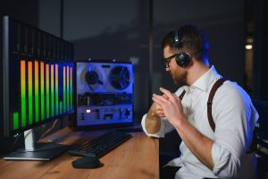 A male spy listens to an illegally recorded conversation surrounded by electronic equipment.
