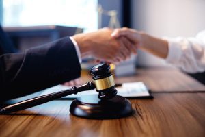 Two people shaking hands with a gavel between them.
