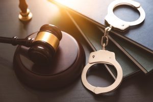 A gavel on a table with books and a pair of handcuffs