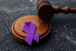 A gavel and purple ribbon on a marble table.