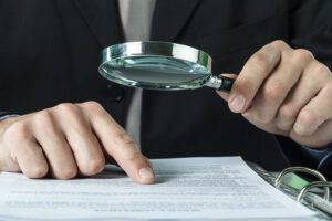 A close-up of a lawyer examining legal documents with a magnifying glass
